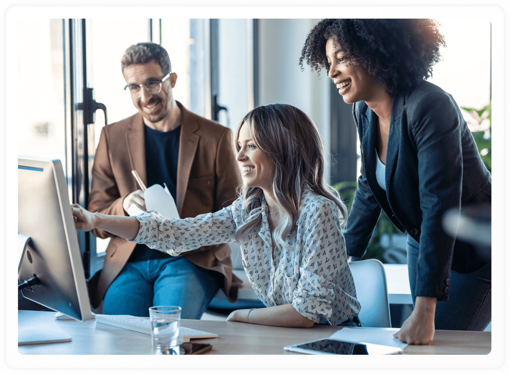 Hero image screenshot of three employees smiling at their work